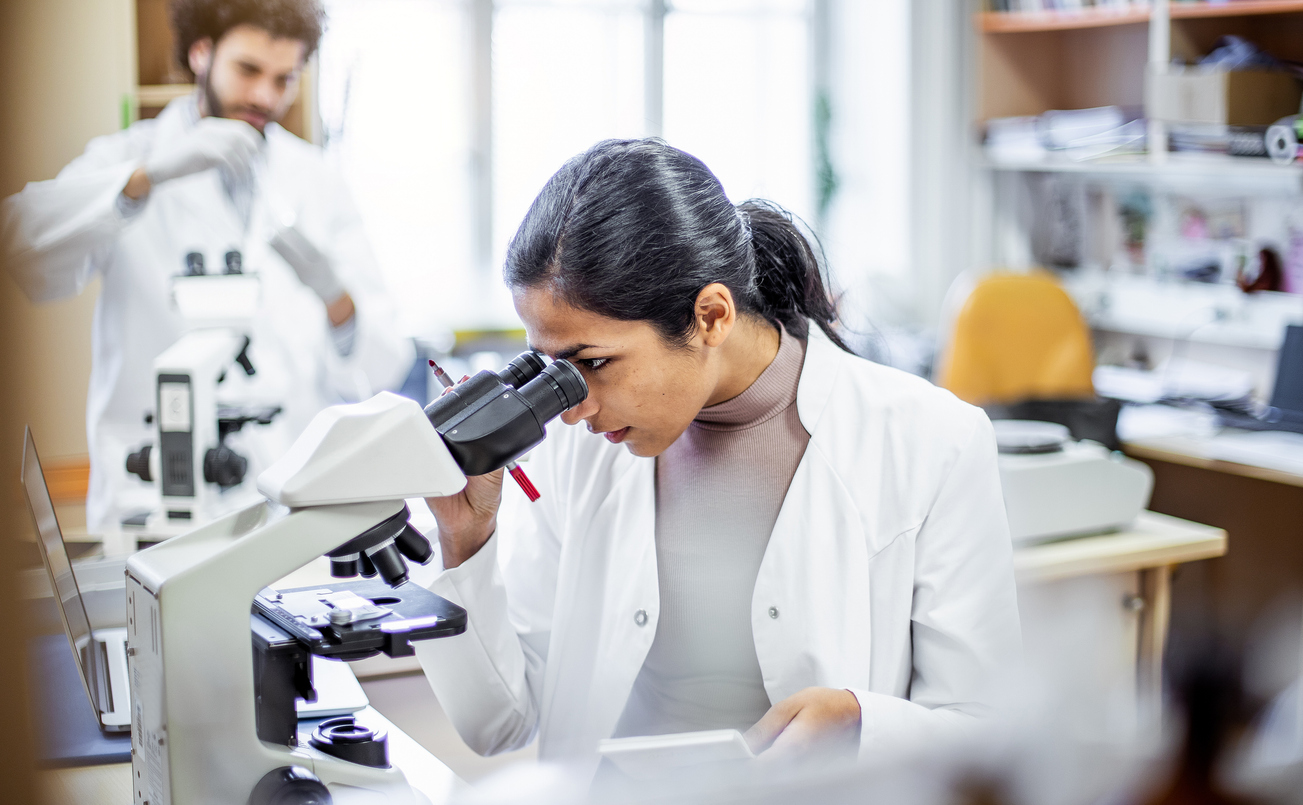A forensic anthropologist uses a microscope to examine a specimen.