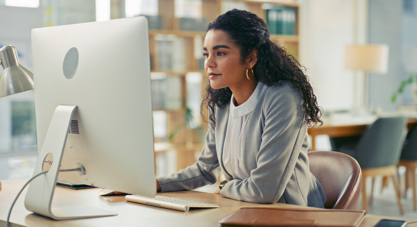 A grant writer develops a proposal on a computer in an office