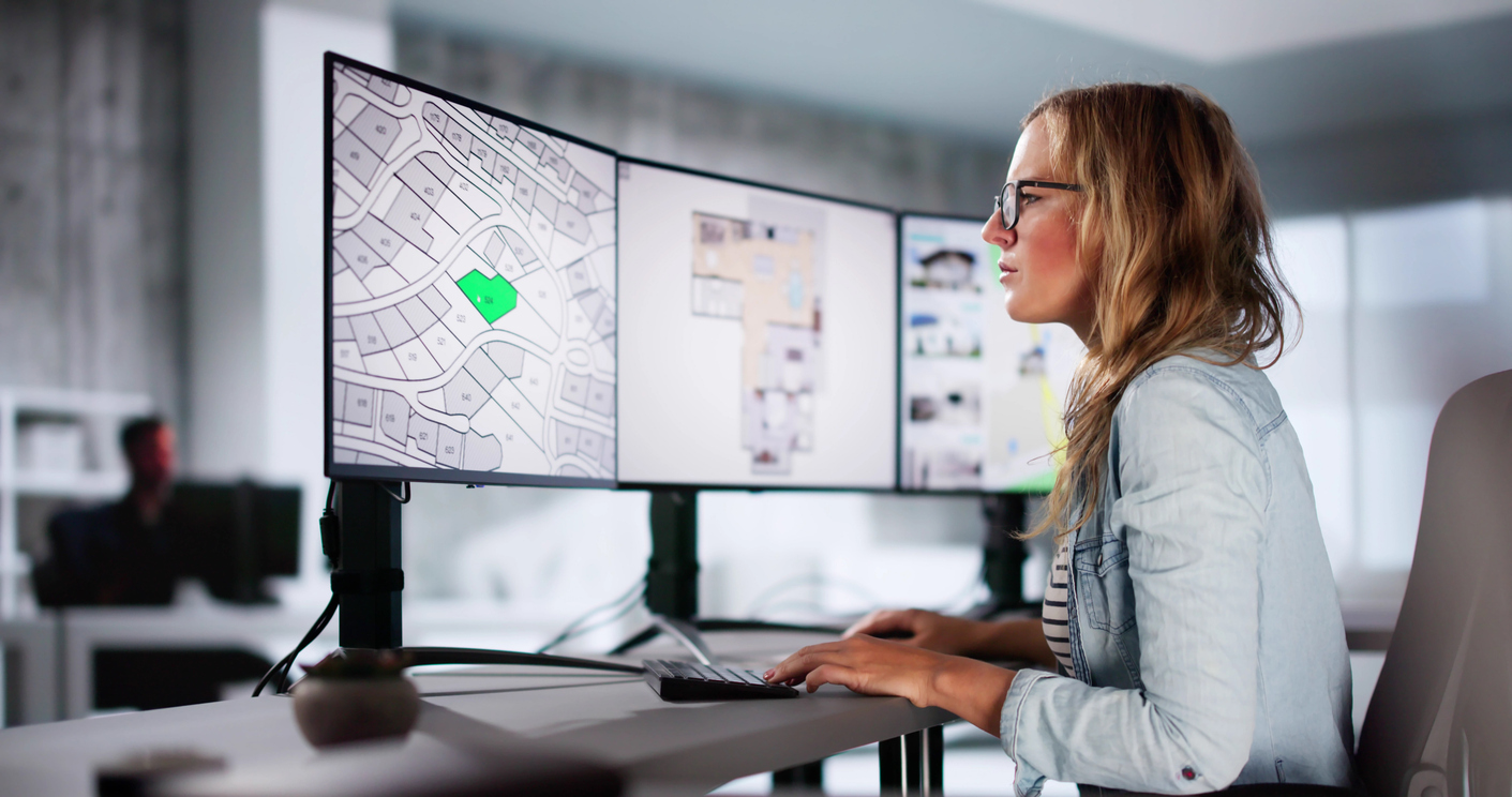 An urban planner reviews a cadastre map on a monitor.