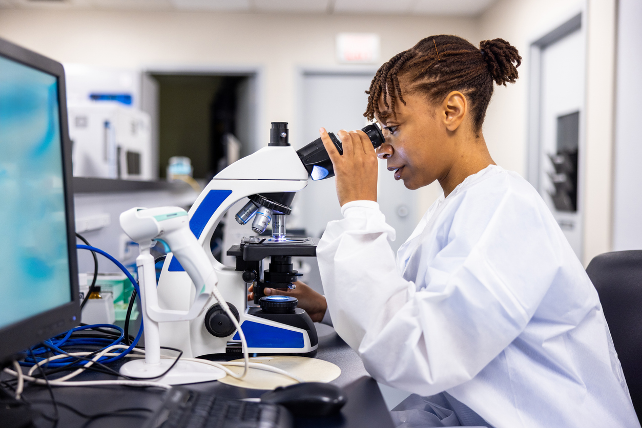 A forensic science technician uses a microscope to analyze a sample.